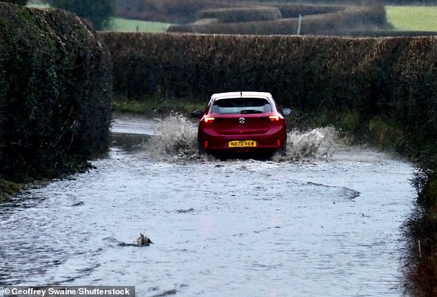 A motorist drives down a flooded country lane in Dunsden, Oxfordshire, on Friday after heavy rain