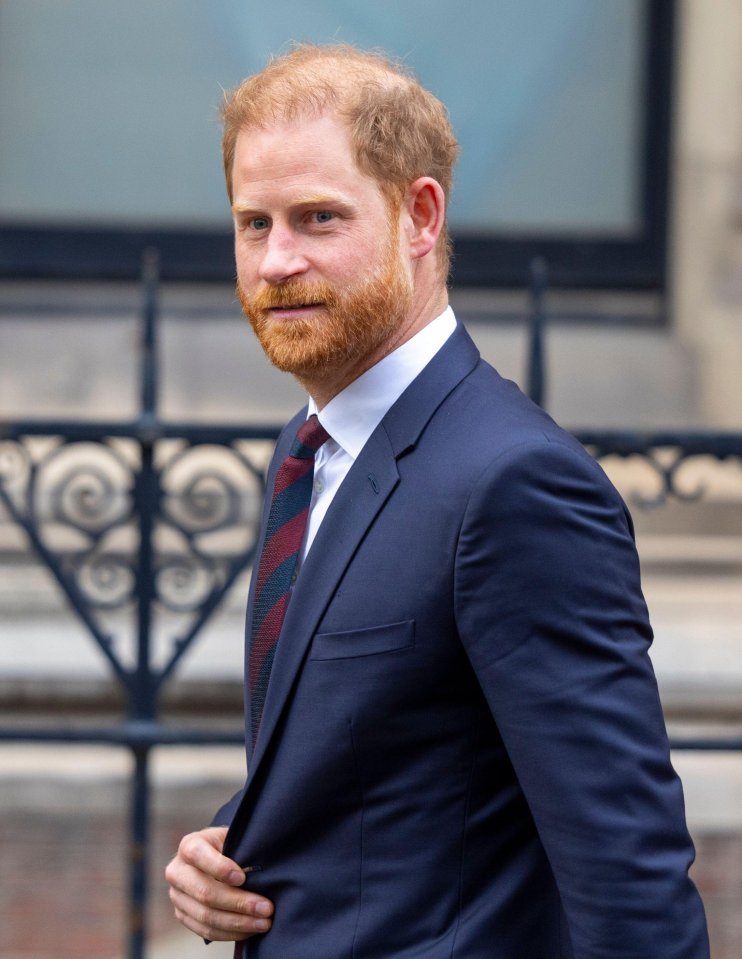 Prince Harry in a navy suit and striped tie leaving the High Court.