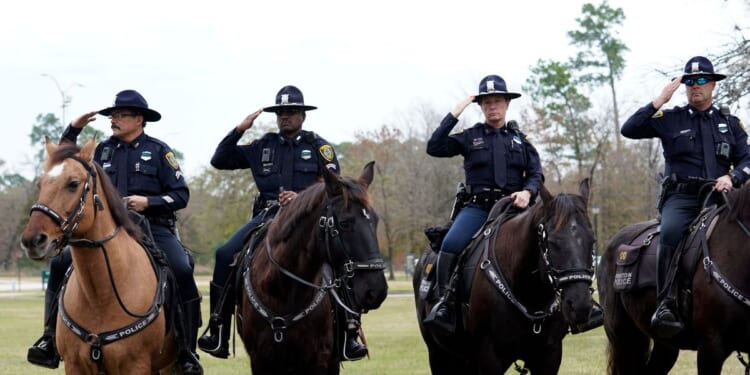 Police on horseback salute as the hearse carrying the flag-draped casket of former President George H.W. Bush heads to the Union Pacific train facility on Dec. 6, 2018, in Houston, Texas.