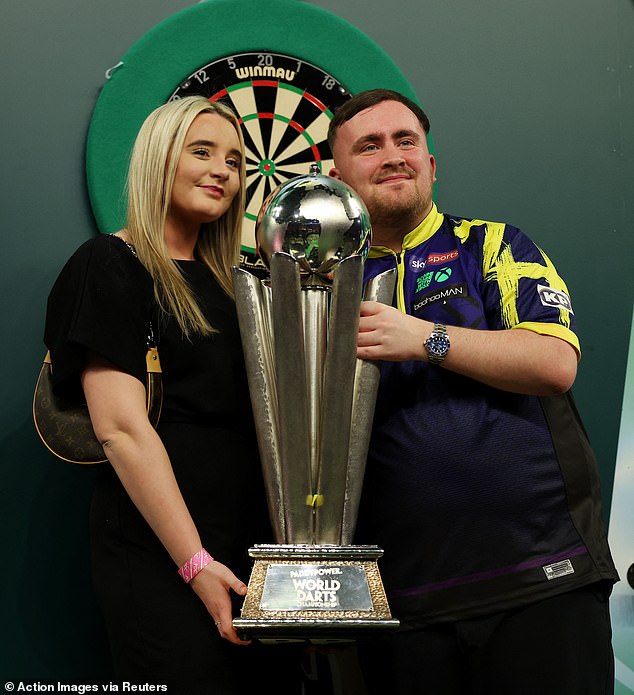 Luke Littler (pictured with his girlfriend Faith Millar) could be set to lose nearly half of his huge £1million prize cheque, after he became the first ever man in 10 years to win back-to-back World Championships at Alexandra Palace