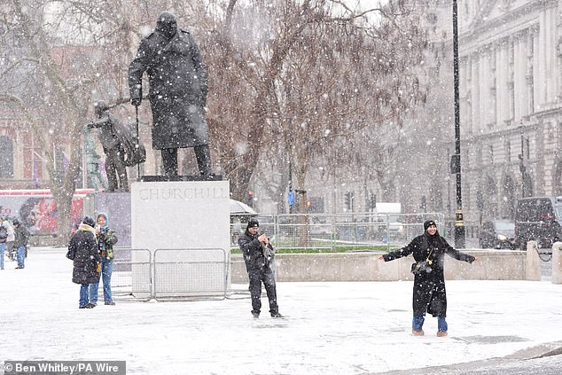 People enjoy the snow in Westminster on Tuesday afternoon as the UK is hit by severe weather