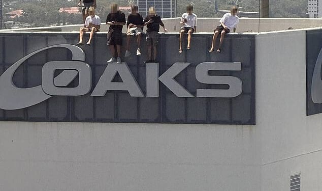 A group of eight boys are seen balancing on top of the Oaks Gold Coast Hotel on Friday