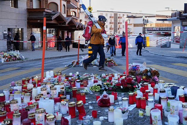 A skier passes candles near the sealed off Le Constellation bar in Crans-Montana, where at least 40 people were killed in a devastating fire during New Year's Eve celebrations