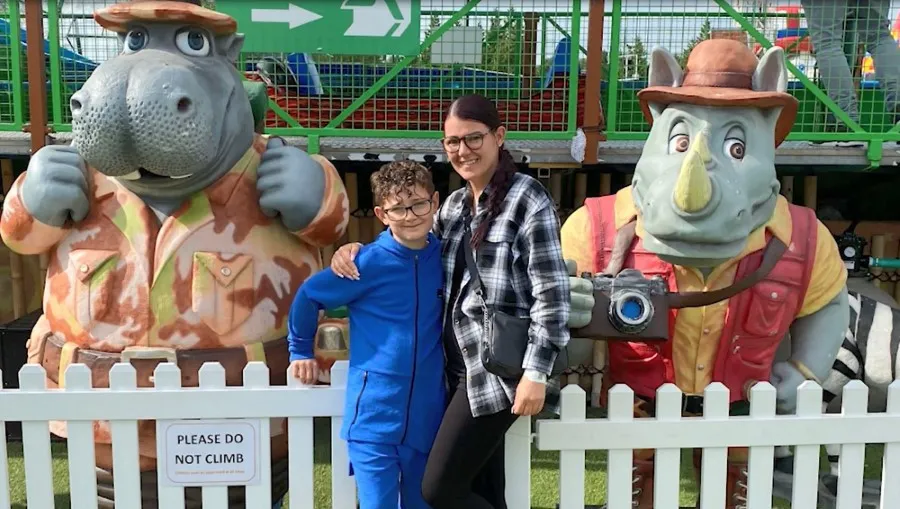 A woman and boy smiling in front of two safari animal statues.