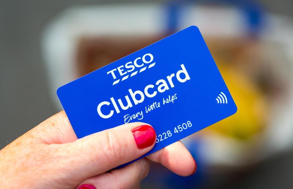 A hand holding a blue Tesco Clubcard.