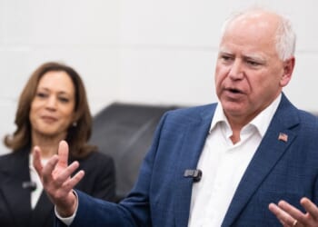 Former Vice President Kamala Harris listens to her running mate, Minnesota Gov. Tim Walz, speak during a visit with members of the marching band at Liberty County High School in Hinesville, Georgia, on Aug. 28, 2024.