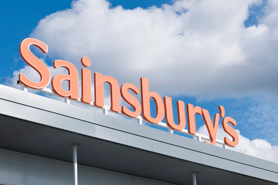 Large orange "Sainsbury's" sign above the entrance to a supermarket in Edinburgh, UK.