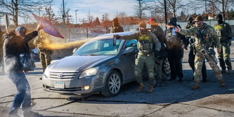 Federal agents use pepper spray against a protester holding a sign during an enforcement operation outside the Whipple Building, an ICE facility in Minneapolis, Minnesota, on Jan. 11, 2026.