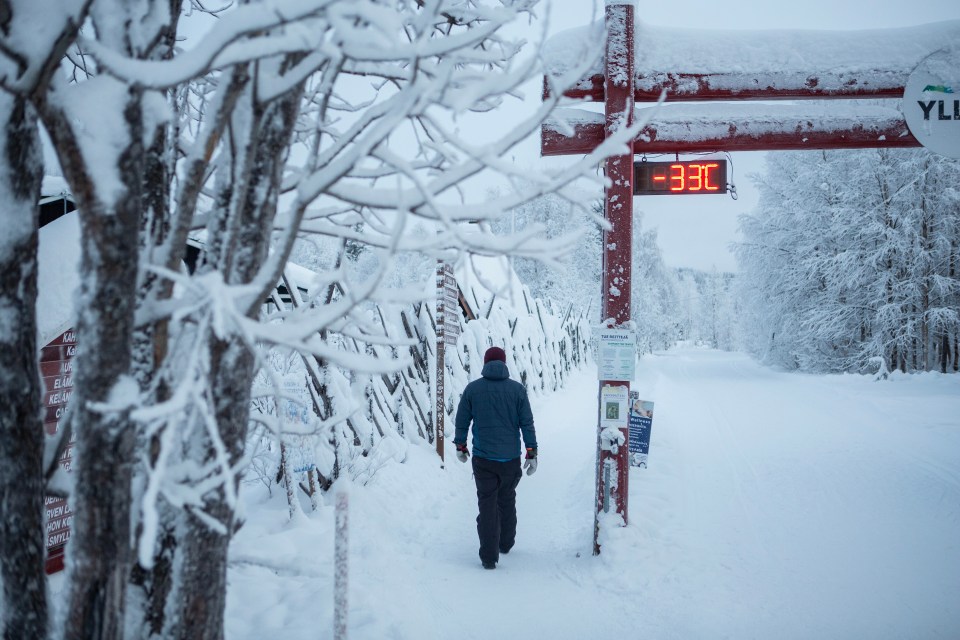 A person walks past a digital display showing a temperature of -33 degrees Celsius in Ylläs, Finland.