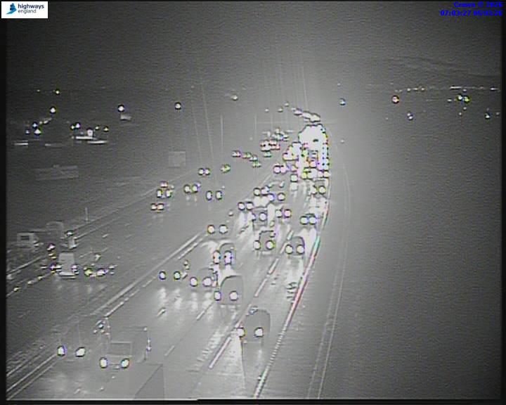 Nighttime overhead shot of highway traffic with car headlights and taillights visible.