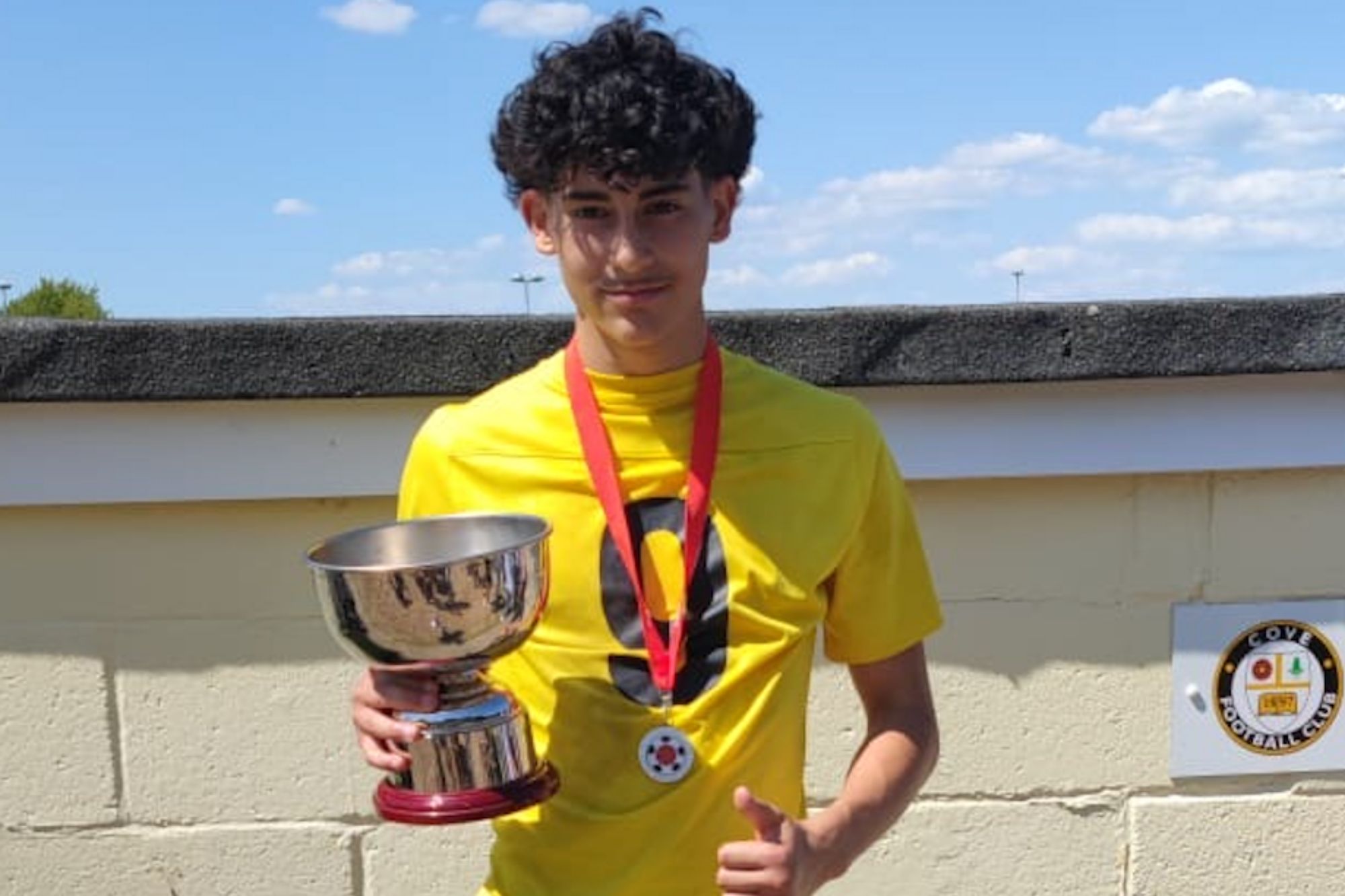 An image collage containing 1 images, Image 1 shows Luis Guembes, a schoolboy, holds a trophy and gives a thumbs-up