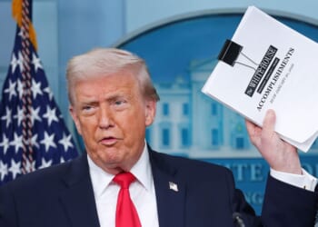 President Donald Trump displays a stack of papers labeled "The White House Accomplishments" as he arrives for a news briefing in the James S. Brady Press Briefing Room of the White House on Jan. 20, 2026, in Washington, D.C.