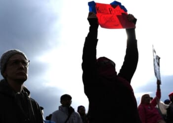 A person holds a sign for Keith Porter, who was shot and killed by an off-duty Immigration and Customs Enforcement officer on New Year's Eve, at a protest and rally against immigration enforcement Sunday, in Seattle.