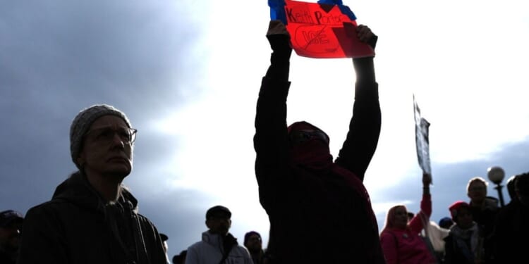 A person holds a sign for Keith Porter, who was shot and killed by an off-duty Immigration and Customs Enforcement officer on New Year's Eve, at a protest and rally against immigration enforcement Sunday, in Seattle.