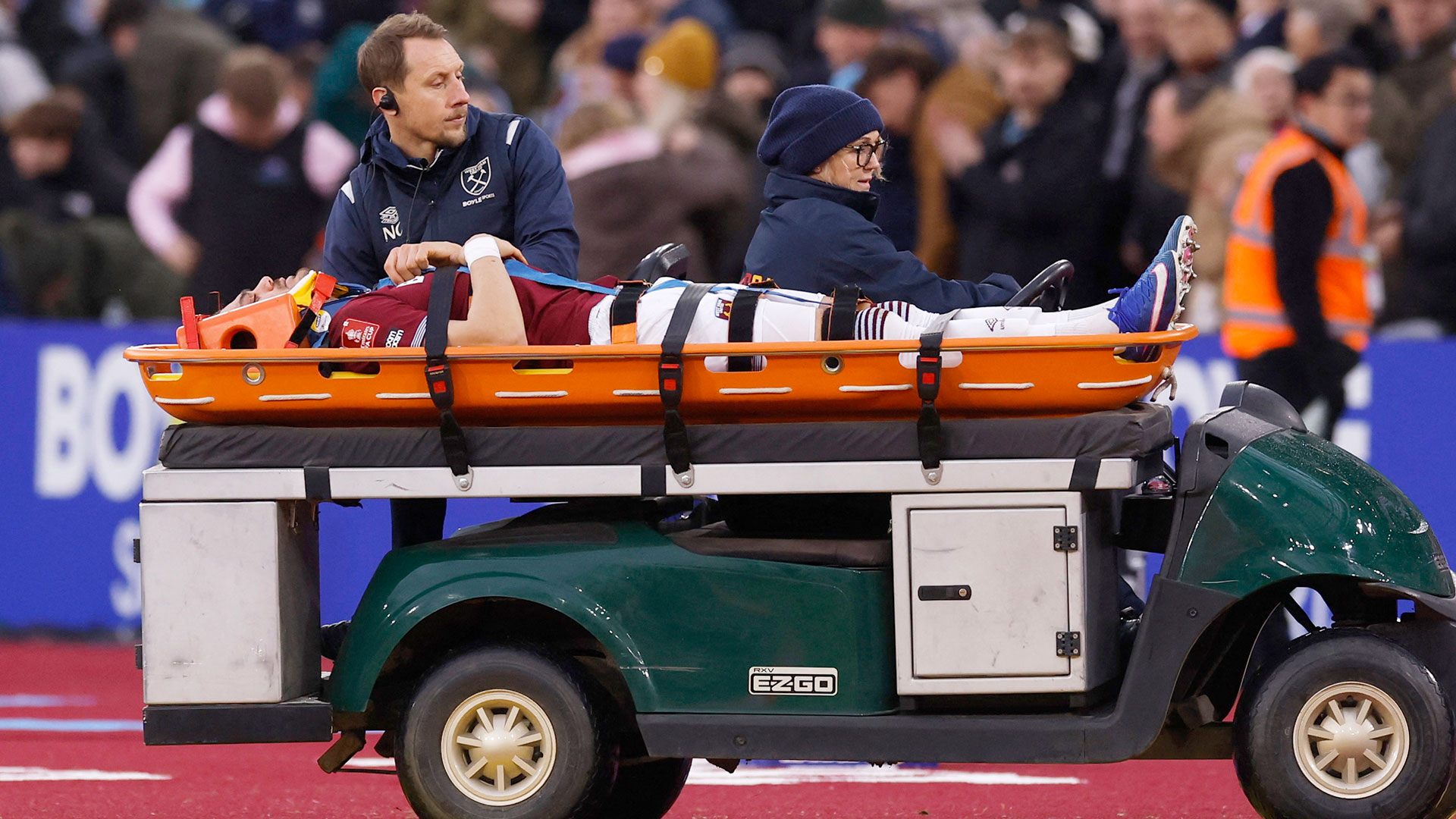 A West Ham player being stretchered off the field on a golf cart.