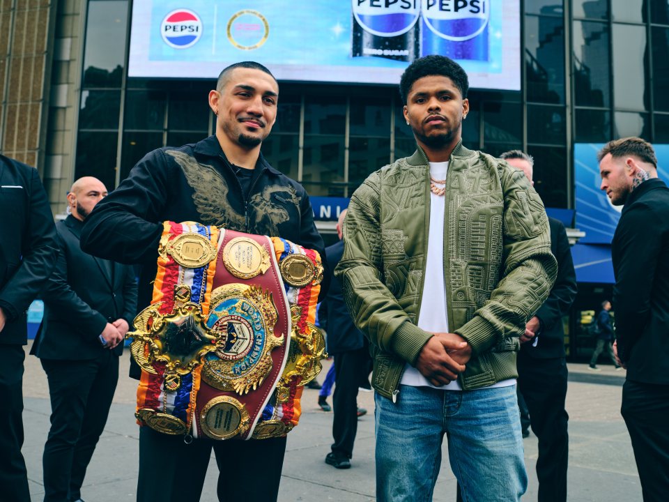 Teofimo Lopez holding his championship belt next to Shakur Stevenson during their press conference.