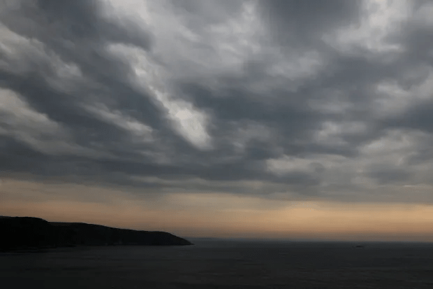 Cloudy skies over a dark ocean at dusk.