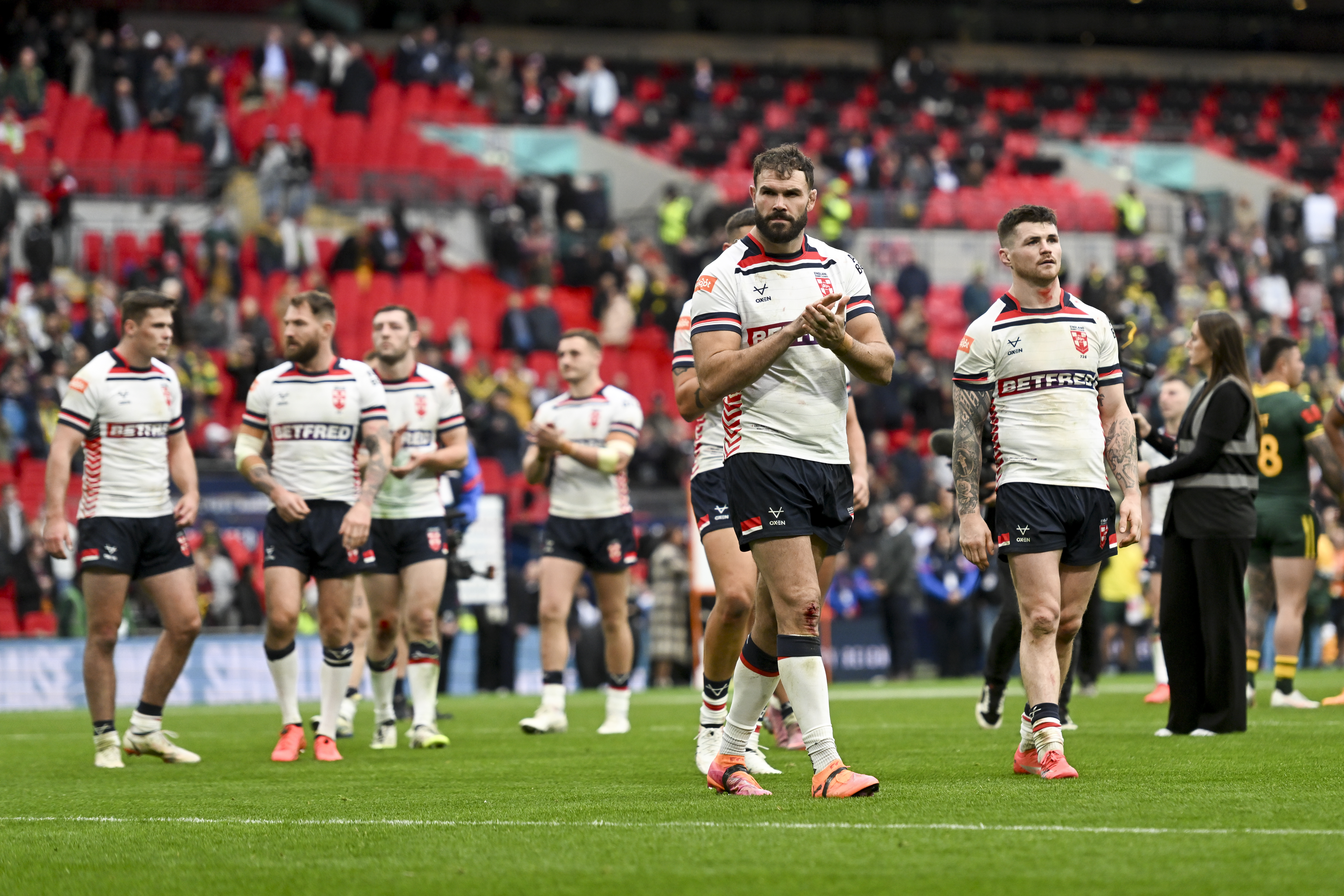 England rugby players in white jerseys on a field.