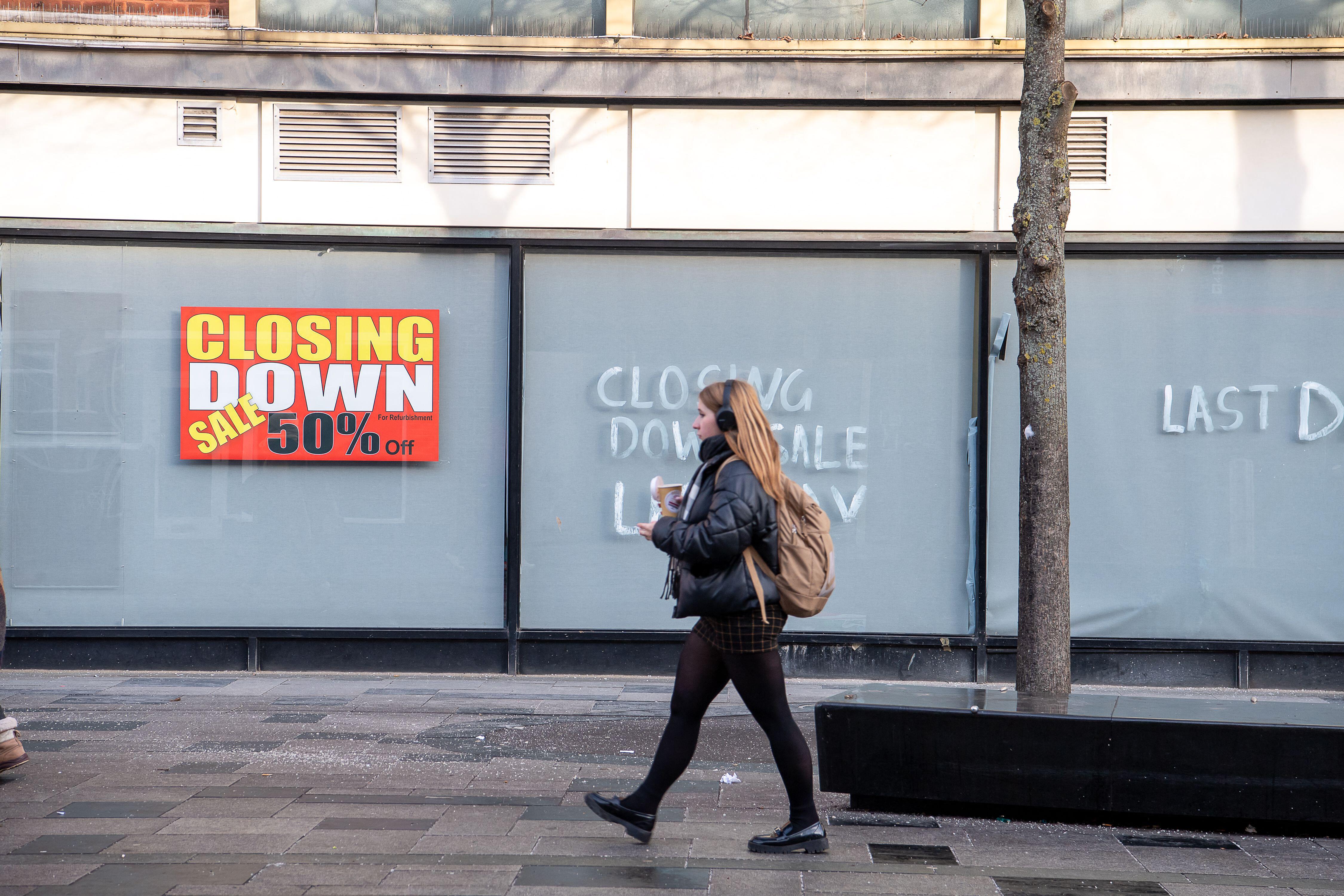 A "Closing Down Sale 50% Off" sign in a store window with a pedestrian walking past in Slough, UK.