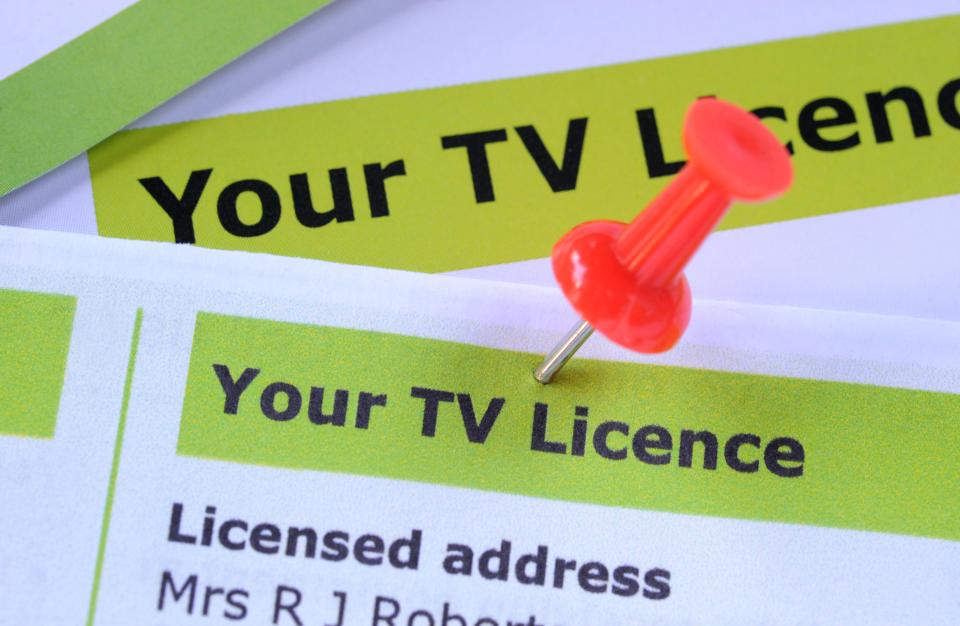 A red thumbtack pinning down a letter with "Your TV Licence" in black text on a green background.