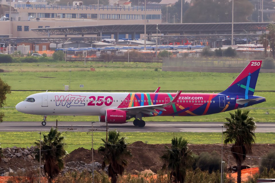 Wizz Air's special commemorative aircraft with "Wizz 250" and colorful livery on the fuselage, taxiing on a runway.