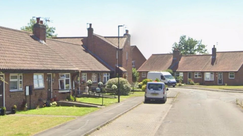 A street view of residential houses with brick facades and tiled roofs.