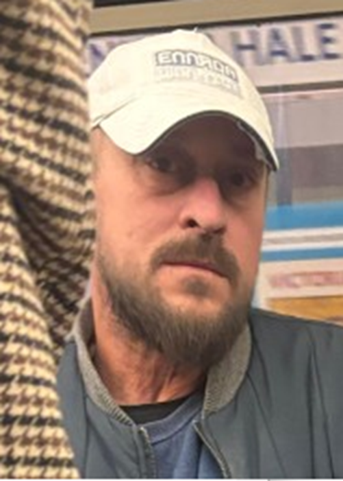 Headshot of a man with a beard and light-colored cap.