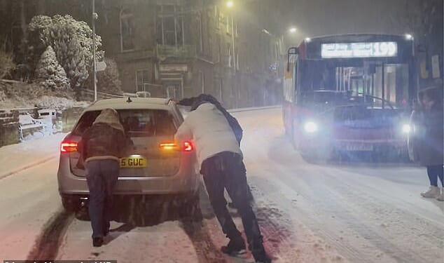 People attempt to push a car stuck in the snow in Buxton, Peak District, Derbyshire, on Thursday night