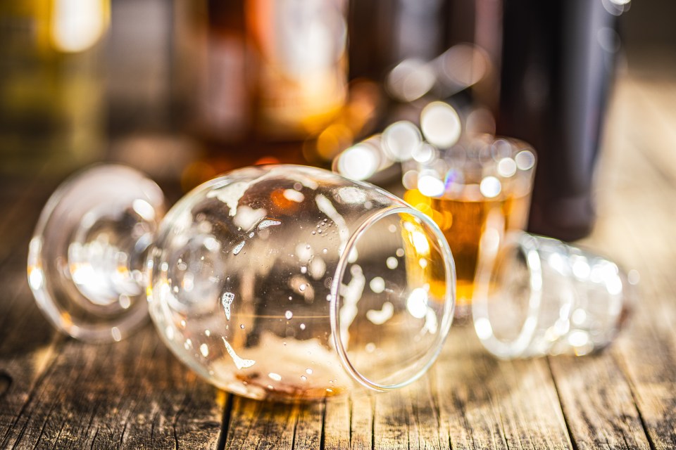 An empty beer glass with foam residue on a wooden table.