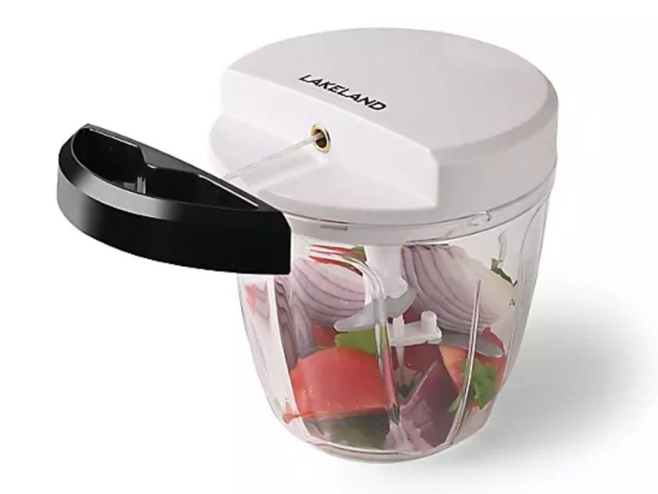 Lakeland manual food chopper with red onion, tomato, and herbs inside.
