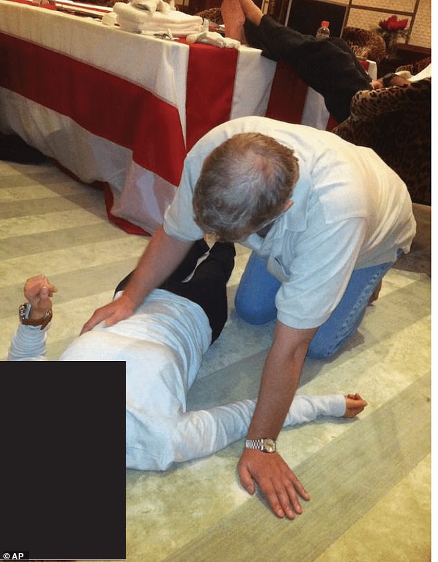 A photograph released in the new documents shows the former Duke of York crouched on all fours, looming over a woman lying flat on the floor