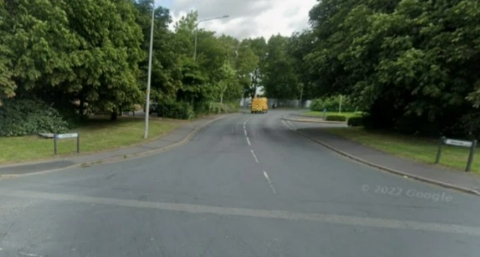 A paved road curving to the right with a yellow van in the distance.