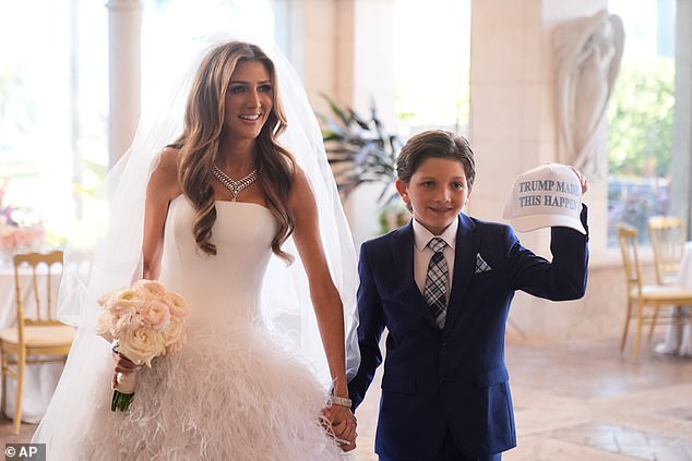 Erin Elmore prepares for her ceremony, holding hands with a young boy who held up a 'Trump Made This Happen' hat