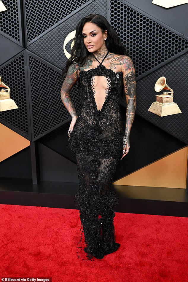 Dare to bare! Singer Kehlani wore a black gown with large cutouts at the chest and stomach. The dress was decorated with beaded flower detailing and featured a halter neckline. However, she chose to forgo accessories and simply wore a pair of diamond stud earrings