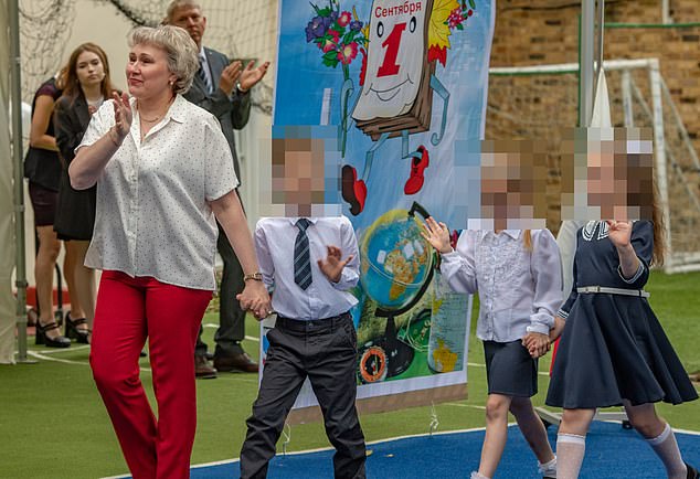 A woman is seen leading a group of young school children across the playground in September 2024