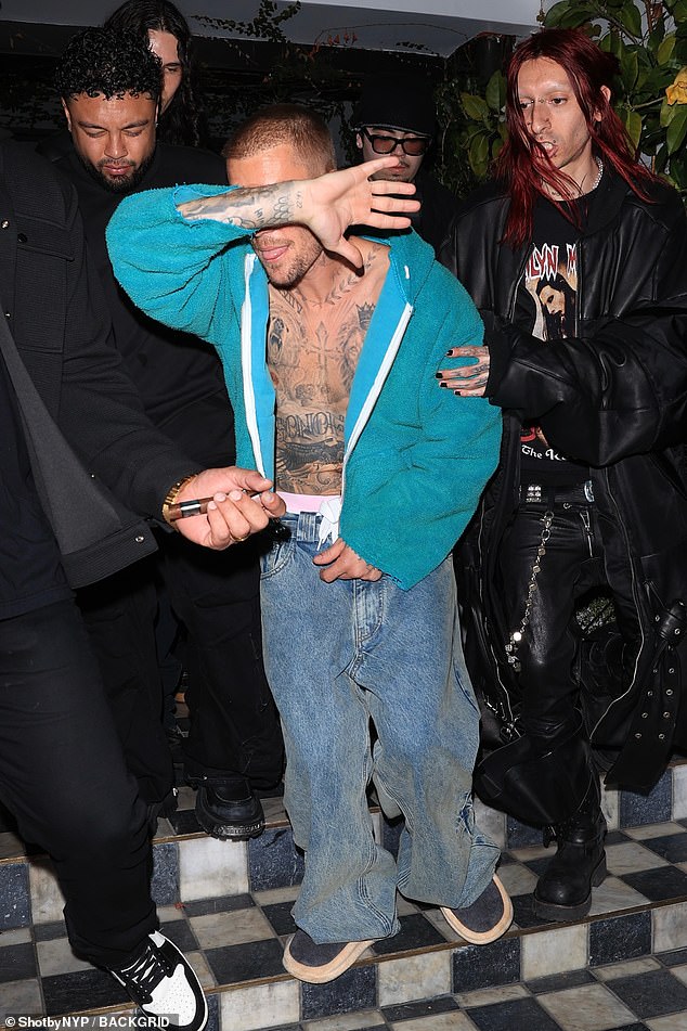 Justin showed off his ripped stomach after unzipping his hoodie while departing the venue