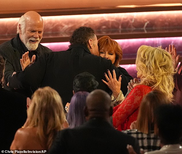 Jelly Roll, center, embraced Reba McEntire as her fiance Rex Linn looked on; to the right is Roll's wife Bunnie Xo