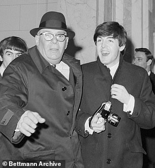 Pictured: Paul McCartney clutches a camera while being ushered to his car outside the Plaza Hotel in 1964