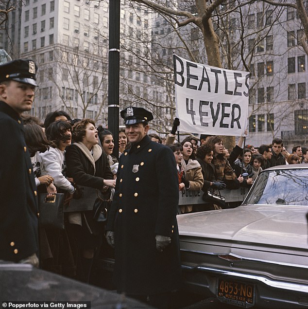 Pictured: Police officers see the funny side as teenagers raise a banner bearing the message 'Beatles 4 Ever' outside the Plaza Hotel in 1964