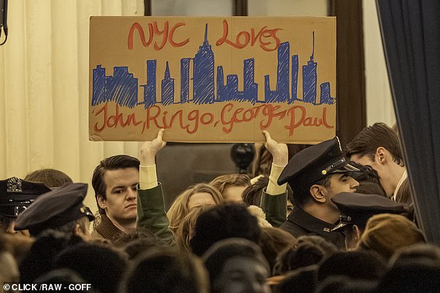 One fan holds up a cardboard sign emblazoned with the message 'NYC loves John, Ringo, George, Paul'