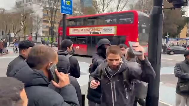 A masked man then comes up behind the preacher and pushes him with force
