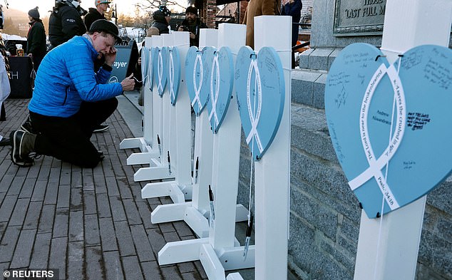 A man reacts as he signs on heart-shaped memorials for each of the victims of the deadly avalanche in the Sierra Nevada mountains before a candlelight vigil for them, in Truckee, California