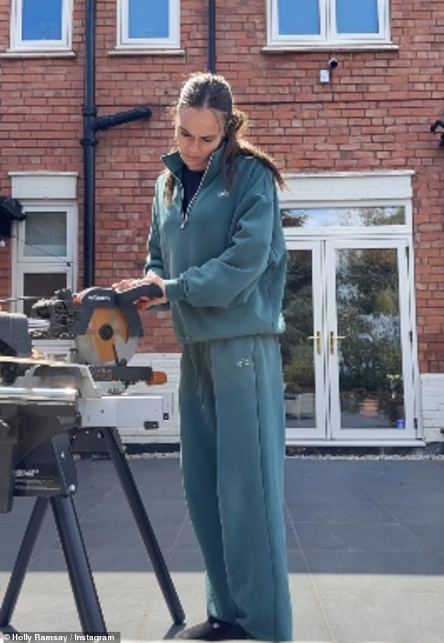 Holly was seen outside in her garden using an electric sander to prepare materials, while wearing a teal Alo half-zip sweatshirt and matching sweatpants