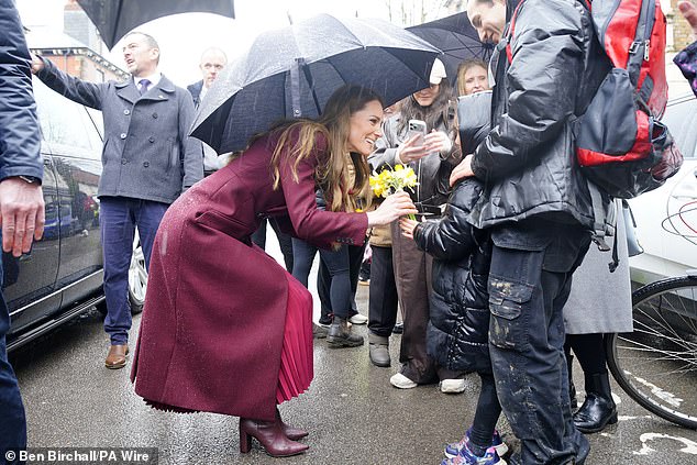 Princess Kate receives some daffodils from a member of the public in the pouring rain