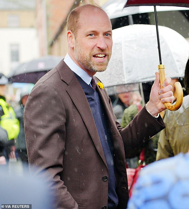 Prince William shields himself from the driving Welsh rain on a visit to Powys, Wales