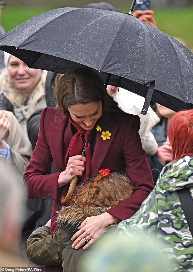 As they greeted members of the public, a little girl wrapped her arms around the Princess as photos showed her burying her face inside Kate's coat in a sweet moment