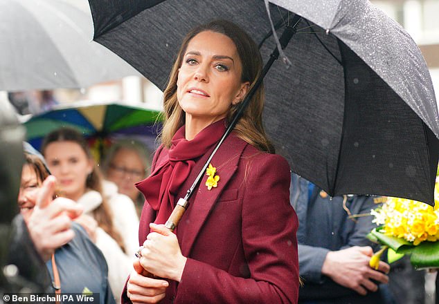 The Princess of Wales shelters from rain under a umbrella whilst meeting members of the public