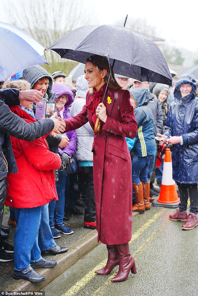 The Princess of Wales shelters from rain under a umbrella whilst meeting members of the public
