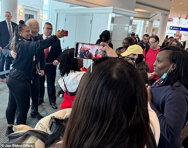 President Joe Biden poses for a selfie as a swarm of onlookers stand around him at the Ronald Reagan Washington National Airport Friday morning in Washington, DC. Biden was on a flight to Columbia, South Carolina