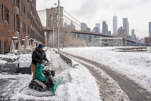 A worker clears snow outside the Empire Stores building in Brooklyn Bridge Park in New York this week